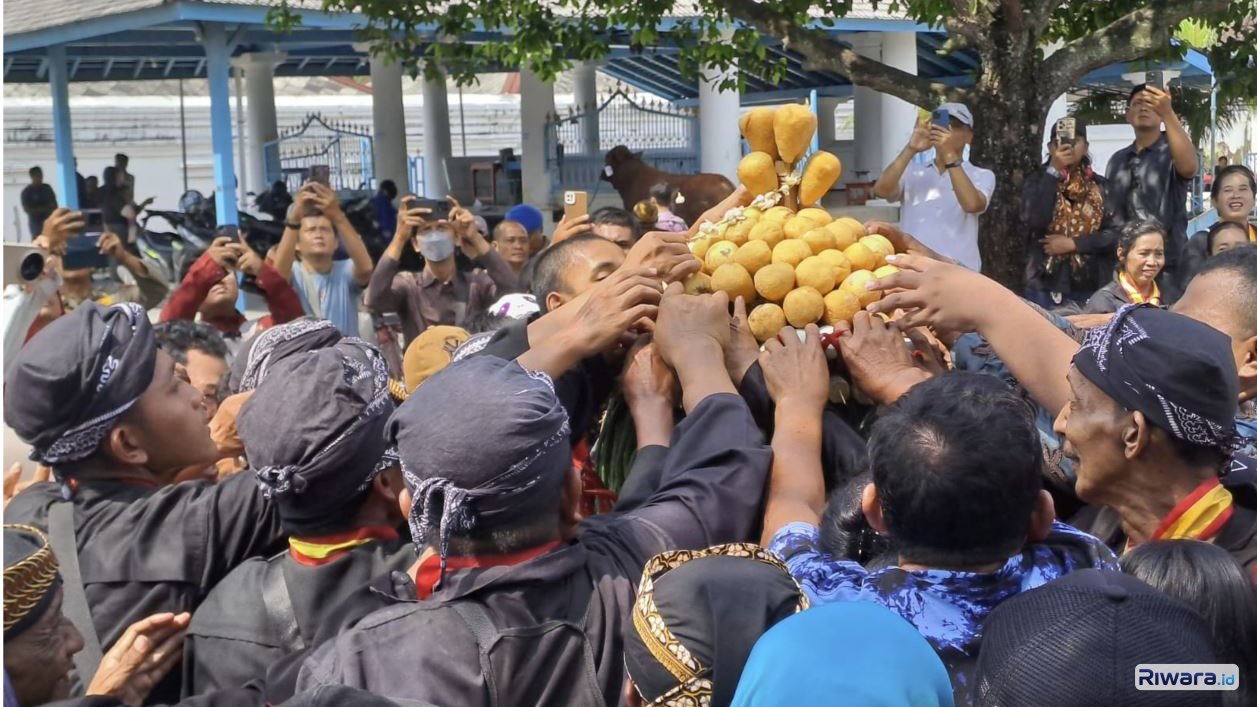 Warga dan abdi dalem Keraton Surakarta berebut gunungan saat Grebeg Besar Tahun Dal di pelataran Masjid Agung